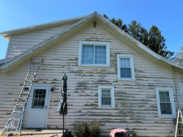 A house exterior with peeling paint and ladders for repainting.