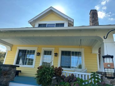 Cozy yellow house with a blue porch and white trim under a clear sky.