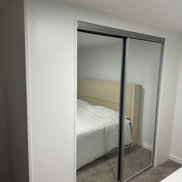 Modern bedroom with mirrored sliding closet doors and beige carpet.