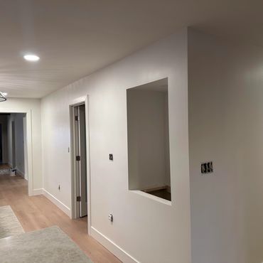 Modern interior hallway with white walls and wooden floor undergoing renovation.