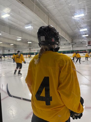 A group of people playing hockey on an indoor rink.