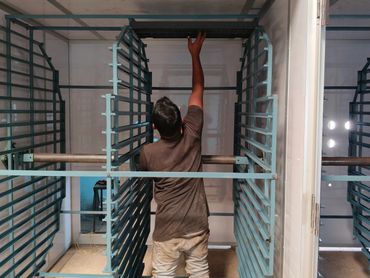 A man reaching up inside a metal rack in a workshop.