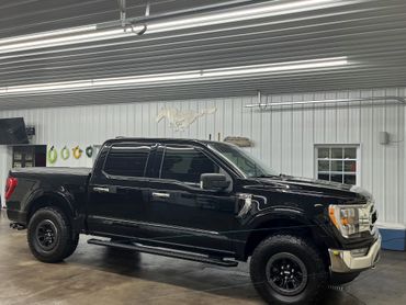 Black pickup truck parked inside a garage with Mustang wall art.