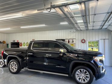 Black GMC Denali truck parked inside a clean garage.