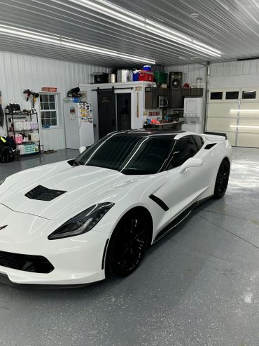 White sports car parked inside a clean, organized garage with various storage and appliances.