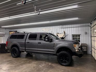 A gray Ford F-250 truck parked inside a metal garage.