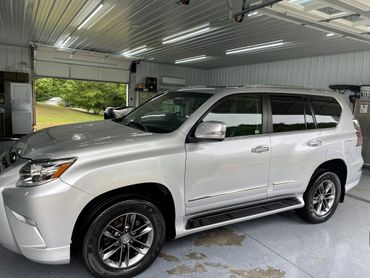 Silver SUV parked inside a clean garage with an open door showing greenery outside.