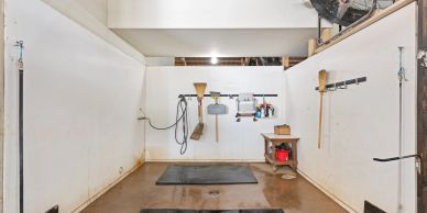 Empty white-walled room with cleaning tools and mats on the floor.