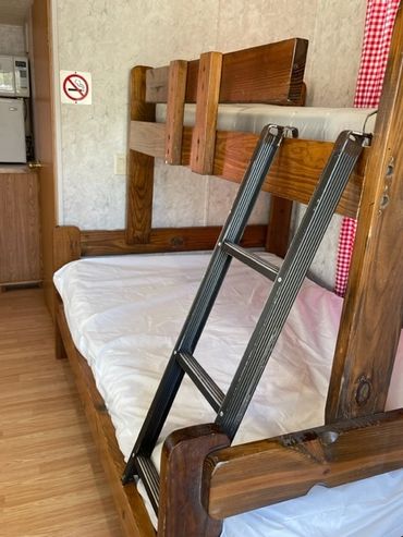 View of full sized bed with single bunk over found in the Deluxe Cabin