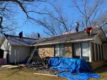 People repairing a residential roof on a clear day.
