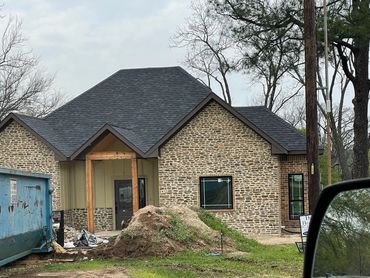 New house under construction with stone facade and blue dumpster.