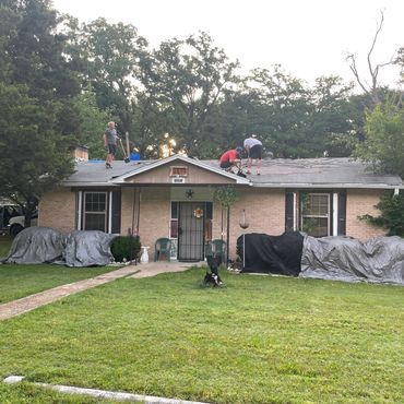 Three men working on a roof of a single-story house.