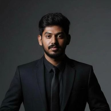 Man in a black suit and tie against a dark background.