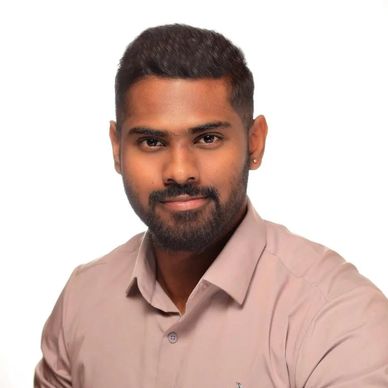 Smiling man with beard in a light brown shirt against white background.