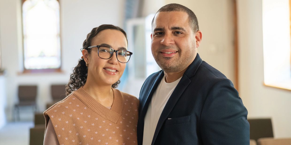 Smiling couple posing indoors with warm natural light.