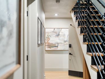 Modern hallway with abstract art and black metal staircase.