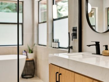 Modern bathroom with double sinks, round mirrors, and a freestanding bathtub.