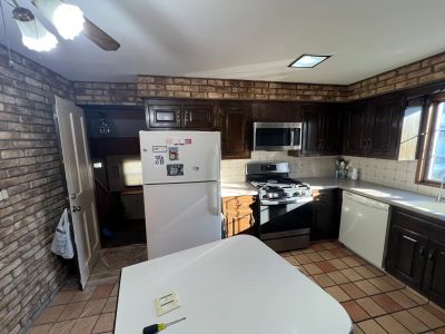 Cozy kitchen with brick walls, white appliances, and dark wooden cabinets.