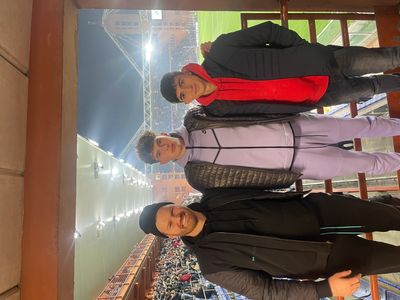 Three young men posing at a stadium during a sports event at night.