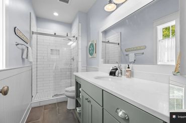 Modern bathroom with glass shower and light green vanity.