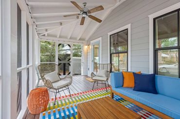 Bright screened porch with colorful rug and modern rattan furniture.