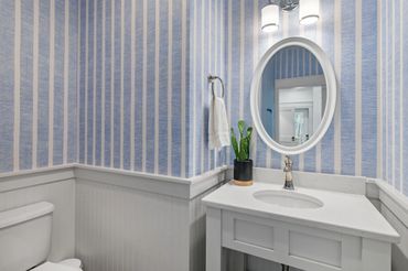 Cozy bathroom with blue striped wallpaper and white vanity.