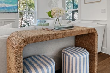 Cozy living room with a woven table and striped stools.