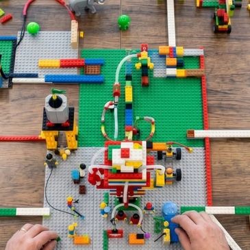 Manos jugando con una construcción de LEGO en una mesa.