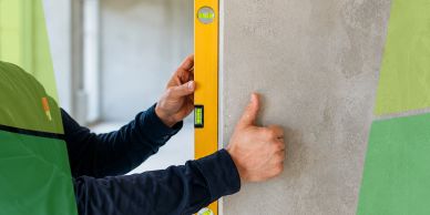 Person checking wall level with a spirit level tool.