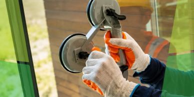 Worker using suction cup tool to install glass.