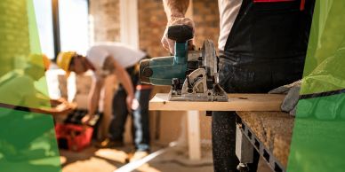Carpenter using a circular saw on wood indoors.