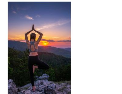 Femme faisant du yoga au coucher du soleil en montagne.