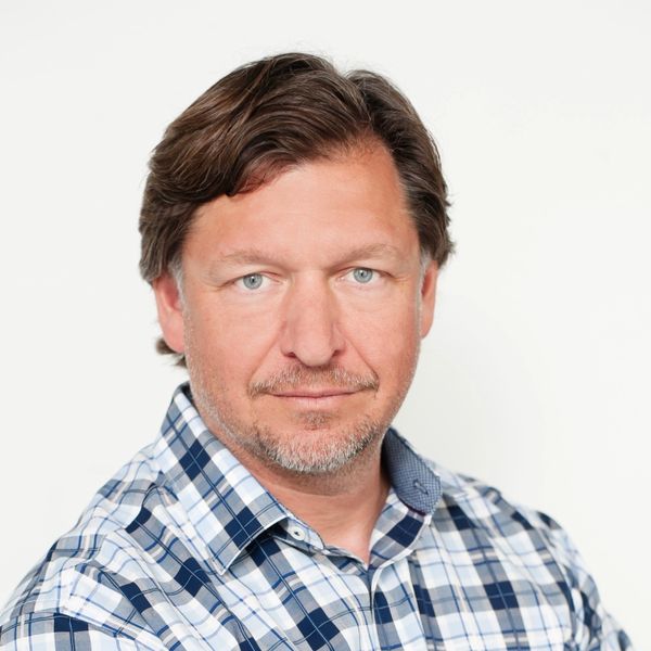 Confident man in a blue checkered shirt against a white background.