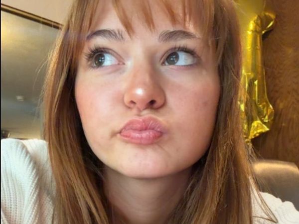 Young woman with light brown hair looking thoughtfully to the side.