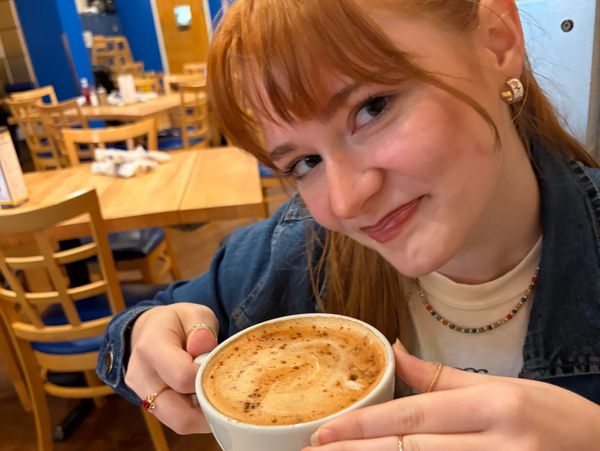 A smiling woman holding a cup of coffee in a cozy café.