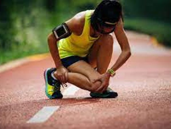 Runner crouched in pain on track holding knee.