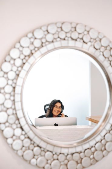 Reflection of vancouver wellness chiropractor receptionist sitting at desk smiling.