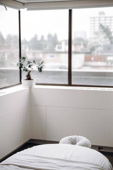 Massage table in room with bright windows.