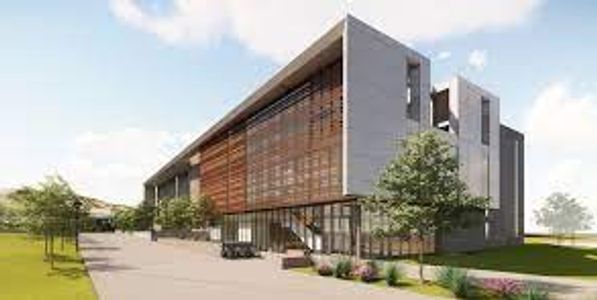 Modern building with glass and wooden panel facade surrounded by greenery.