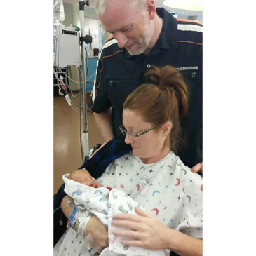 New parents lovingly hold their Trisomy 18 newborn in a hospital room.