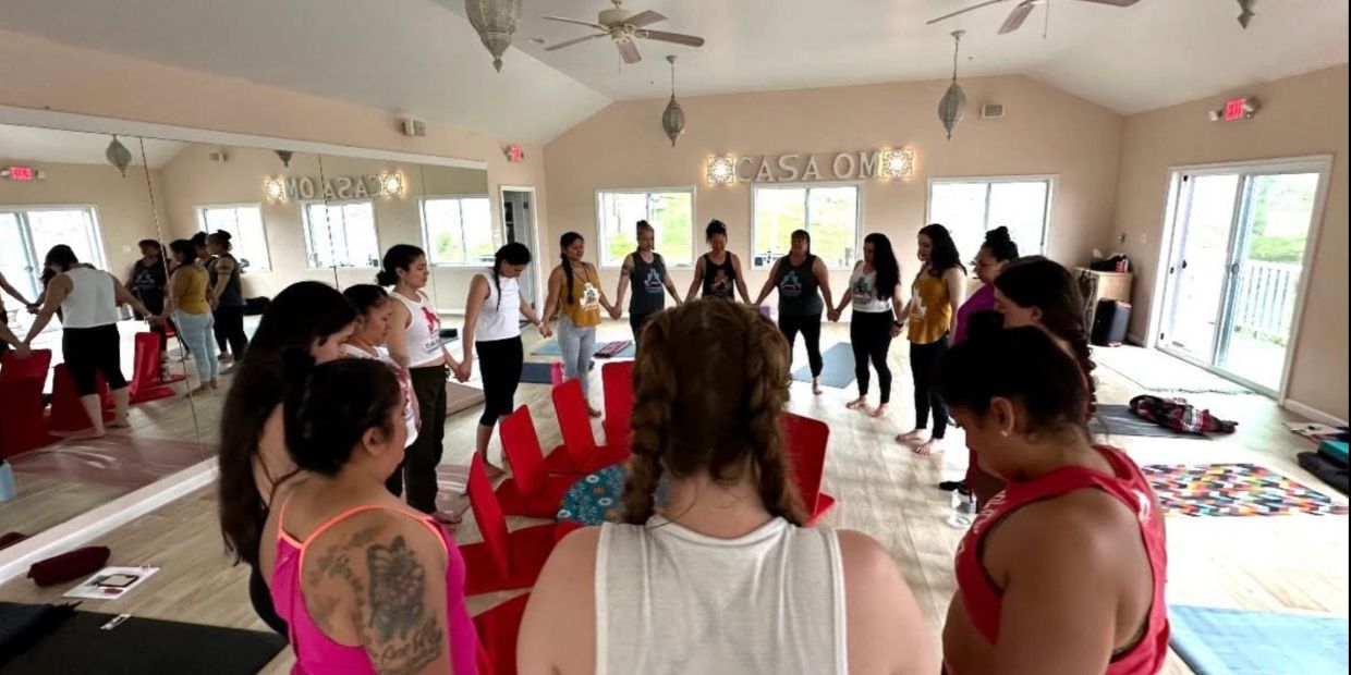Group of women holding hands in a circle at Casa Om yoga studio.