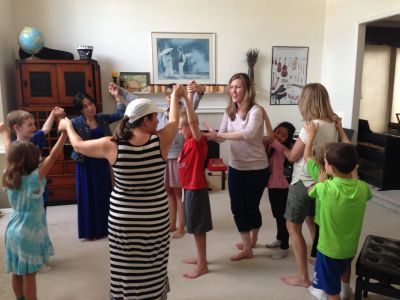 Group of adults and children dancing in a living room.