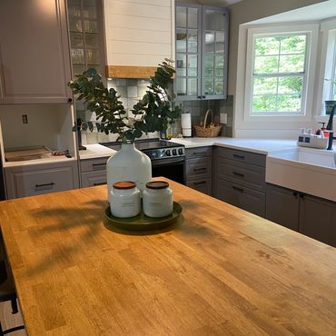 Modern kitchen with wooden island and decorative jars with greenery.