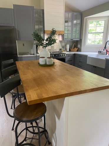 Modern kitchen with wooden countertop and gray cabinets.
