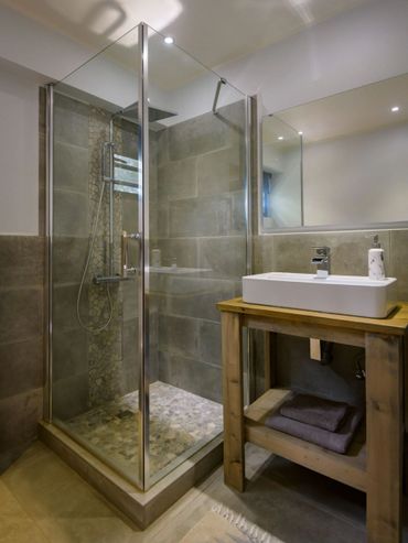 Modern bathroom with glass shower and wooden vanity.