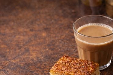 A glass of tea with a piece of crispy rice cake on a wooden surface.