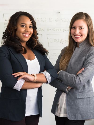 Two confident women standing with arms crossed in a professional setting.