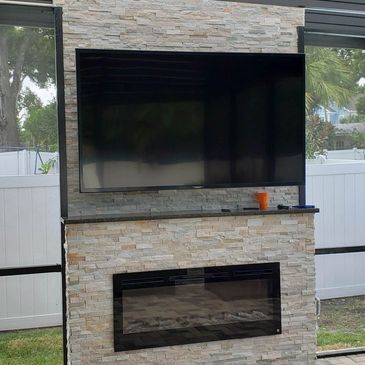 Outdoor fireplace with a mantel and a TV