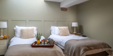 Cozy twin beds with beige accents and a breakfast tray in a softly lit bedroom.
