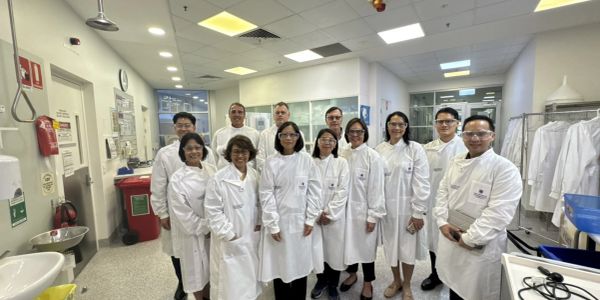 Group of scientists in lab coats posing together in a laboratory.